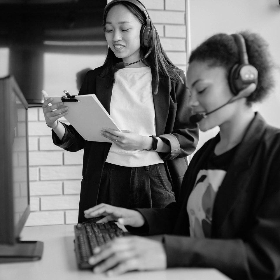 Two colleagues at a help desk, wearing headsets